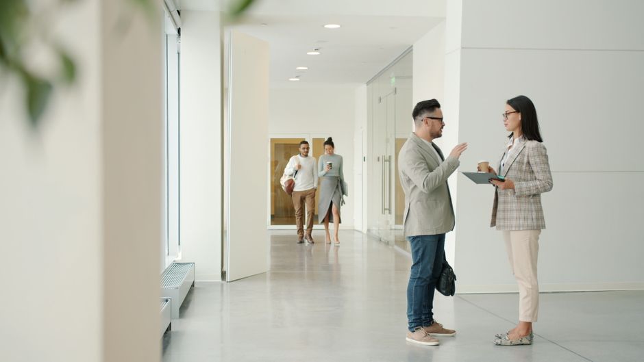 A diverse group of three professionals in a bright, modern office collaboratively looking at a tablet, symbolizing a team of experts working together on a plan.